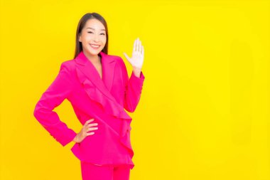 Güzel bir Asyalı kadın sarı arka planda gülümsüyor.