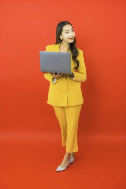 Portre güzel genç iş kadını Asyalı kadın kırmızı arka planda bilgisayar bilgisayarı kullanıyor