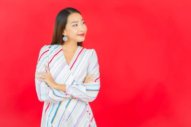 Güzel bir Asyalı kadının portresi kırmızı arka planda birçok hareketle gülümsüyor.