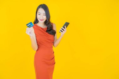 Renkli arka planda akıllı cep telefonuyla güzel Asyalı kadın gülümsemesi