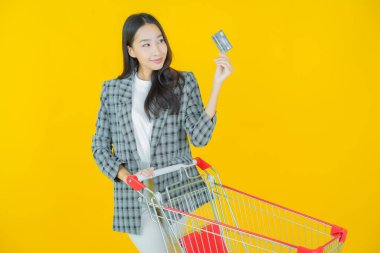 Renkli arka planda süpermarketten alınmış market sepetiyle gülümseyen güzel Asyalı kadın portresi.