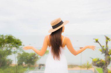 Portriat güzel genç Asyalı kadın deniz manzaralı balkonda mutlu bir gülümseme