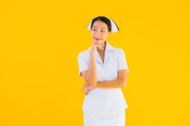 Güzel Asyalı genç Taylandlı hemşirenin portresi klinikteki ve hastanedeki hastalar için sarı izole edilmiş arka planda birçok eylem çalışmasında yer alıyor.