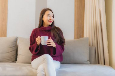 Oturma odasının iç tarafındaki kanepeye kahve fincanı asyalı güzel bir kadının portresi.
