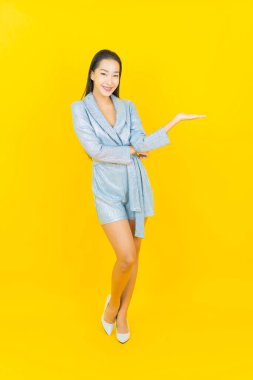 Asyalı güzel bir kadının portresi. Sarı arka planda hareketli gülümsüyor.