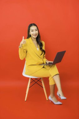 Portre güzel genç iş kadını Asyalı kadın kırmızı arka planda bilgisayar bilgisayarı kullanıyor