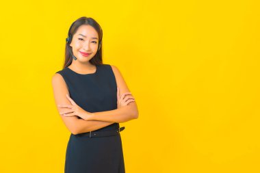 Sarı arka planda kulaklık takmış güzel Asyalı iş kadını portresi.