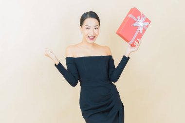 Güzel bir Asyalı kadının portresi. Arka planda kırmızı hediye kutusuyla gülümsüyor.