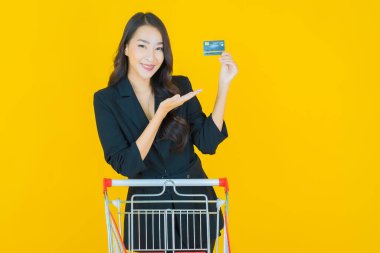 Renkli arka planda süpermarketten alınmış market sepetiyle gülümseyen güzel Asyalı kadın portresi.