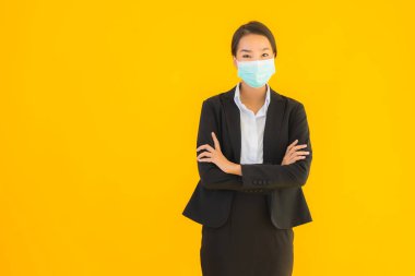 Güzel genç iş kadını portresi Korunmak için maske takıyor 19 koronavirüs sarı izole arka planda