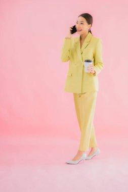 Güzel Asyalı iş kadını portresi. Arka planda kahve fincanı ve akıllı cep telefonu kullanıyor.