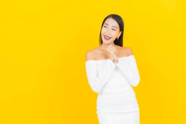 Portre güzel genç iş kadını gülümseyen ve eylem sarı arka planlı Asyalı kadın