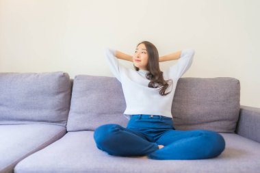 Portre güzel genç Asyalı kadın rahatla kanepede gülümse oturma odasında