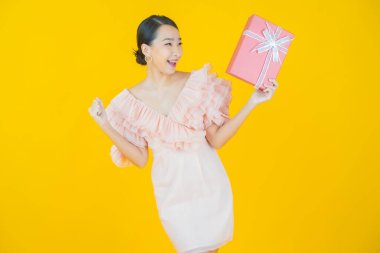 Güzel bir Asyalı kadının portresi. Arka planda kırmızı hediye kutusuyla gülümsüyor.