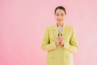 Güzel Asyalı iş kadını portresi. Kaşığı ve çatalı var. Pembe renkli arka planda yemeye hazır.