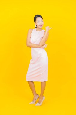 Asyalı güzel bir kadının portresi. Sarı arka planda hareketli gülümsüyor.