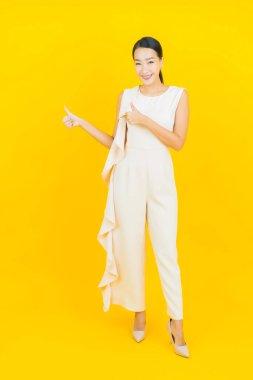 Asyalı güzel bir kadının portresi. Sarı arka planda hareketli gülümsüyor.