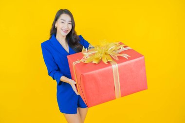 Güzel bir Asyalı kadının portresi. Arka planda kırmızı hediye kutusuyla gülümsüyor.