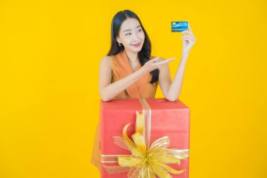 Güzel bir Asyalı kadının portresi. Arka planda kırmızı hediye kutusuyla gülümsüyor.