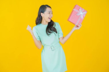 Güzel bir Asyalı kadının portresi. Arka planda kırmızı hediye kutusuyla gülümsüyor.