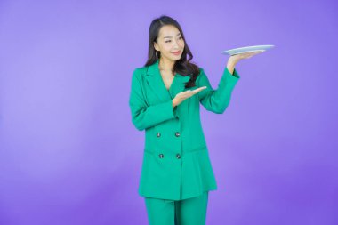 Güzel Asyalı bir kadının portresi. Arka planda boş tabak tabağıyla gülümsüyor.