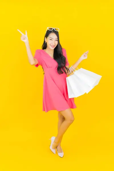 Porträt Schöne Junge Asiatische Frau Lächeln Mit Einkaufstasche Auf Gelbem lizenzfreie Stockfotos