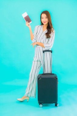 Güzel Asyalı bir kadının portresi. Bavul pasaportu ve biniş kartı mavi arka planda seyahat için hazır.