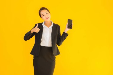 Portre güzel genç Asyalı kadın akıllı cep telefonu ve kahve fincanı ile izole edilmiş sarı arka planda