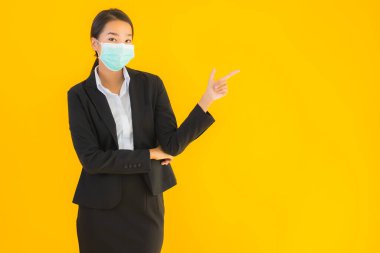 Güzel genç iş kadını portresi Korunmak için maske takıyor 19 koronavirüs sarı izole arka planda