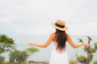 Portriat güzel genç Asyalı kadın deniz manzaralı balkonda mutlu bir gülümseme