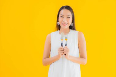 Sarı izole arka planda çatal kaşıklı güzel bir Asyalı kadın portresi.
