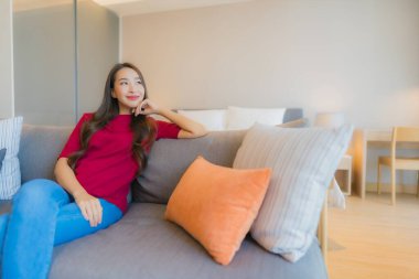 Güzel bir Asyalı kadın portresi. Yatak odasındaki kanepede rahatla. Gülümse.