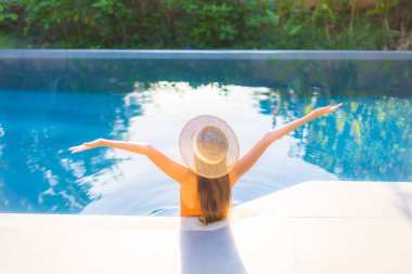 Güzel bir Asyalı kadının portresi tatil için yüzme havuzunda rahatlıyor.