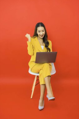 Portre güzel genç iş kadını Asyalı kadın kırmızı arka planda bilgisayar bilgisayarı kullanıyor
