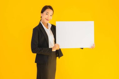 Güzel bir portre. Genç Asyalı kadın, sarı izole edilmiş arka planda boş beyaz tahta gösteriyor.