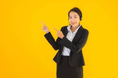 Portre güzel genç Asyalı kadın kulaklık ya da çağrı merkezi için kulaklık ya da tele pazarlama sarı izole arka planda.