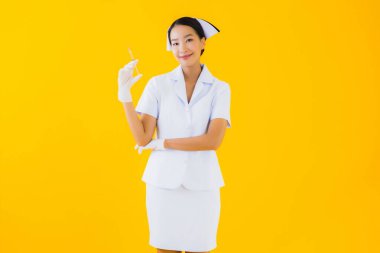 Asyalı güzel bir kadının portresi. Taylandlı hemşire, sarı izole edilmiş arka planda eldiven giyiyor.