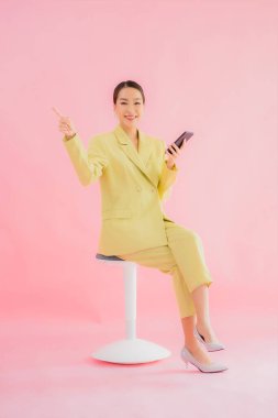 Güzel Asyalı iş kadını portresi. Arka planda kahve fincanı ve akıllı cep telefonu kullanıyor.