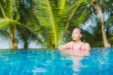 Portre güzel Asyalı kadın gülümsemesi tatil gezisinde tatil otelinde yüzme havuzunda rahatla.