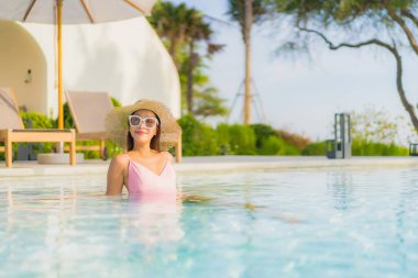 Güzel bir Asyalı kadın portresi. Tatil gezisinde deniz manzaralı açık havuz etrafında rahatça yüzebiliyor.