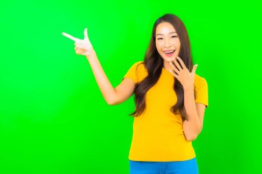 Asyalı güzel bir kadının portresi yeşil izole edilmiş arka planda hareketle gülümsüyor.