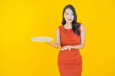 Güzel Asyalı bir kadının portresi. Arka planda boş tabak tabağıyla gülümsüyor.