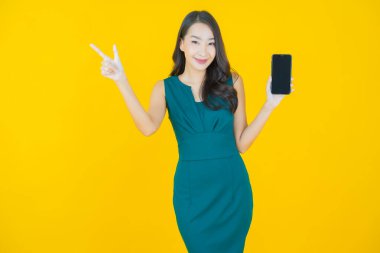 Renkli arka planda akıllı cep telefonuyla güzel Asyalı kadın gülümsemesi