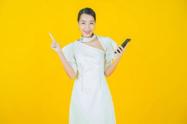 Renkli arka planda akıllı cep telefonuyla güzel Asyalı kadın gülümsemesi