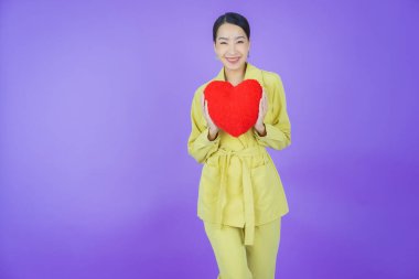 Portre güzel Asyalı genç kadın gülümsüyor kalp yastığı şeklinde renk arkaplan