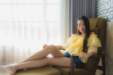 Portre genç Asyalı kadın rahatla. Oturma odasındaki koltukta gülümse.