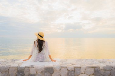 Güzel Asyalı genç kadınların portresi mutlu bir gülümseme deniz kıyısında güneş doğarken ya da batarken rahatla