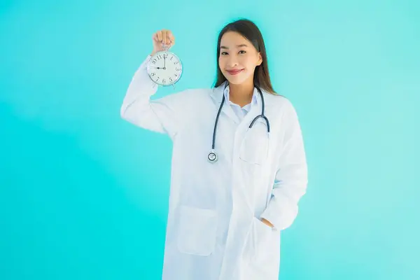 stock image Portrait beautiful young asian doctor woman with clock or alarm on blue isolated background