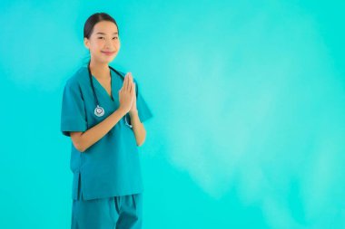 Portrait beautiful young asian doctor woman happy smile with sawasdee for work in hospital and clinic on blue isolated background clipart