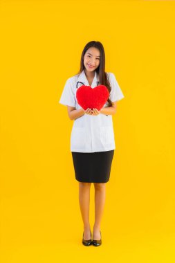 Güzel bir portre genç Asyalı doktor kadın, sarı izole edilmiş arka planda aşkın sembolü için kalbini göster.